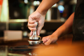 Barista skillfully pouring steamed milk into a cup of espresso, creating latte art in a cozy café during a busy morning.