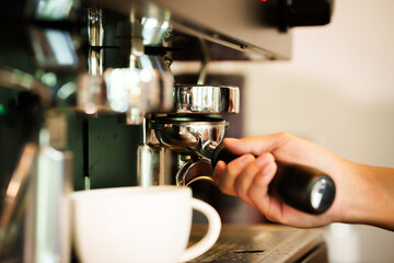 Barista skillfully pouring steamed milk into a cup of espresso, creating latte art in a cozy café during a busy morning.