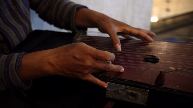 Close up of a man's hand playing the traditional Javanese plucked instrument, the siter