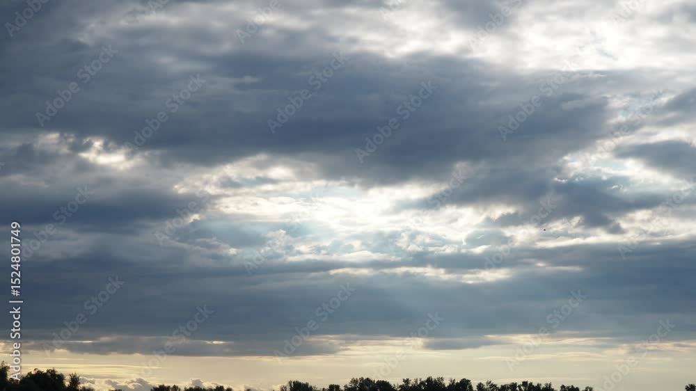 Poster Witness the captivating journey of light slicing through layered clouds during twilight, showcasing natures artistry in a serene landscape. A transformative display unfolds overhead.