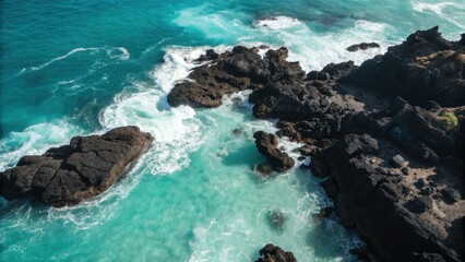 Waves crash against rugged black volcanic rocks in turquoise ocean from aerial perspective, revealing vibrant sea textures and natural coastline. 