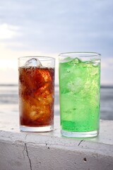 Green and cola soft drink and ice cubes