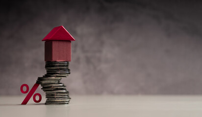 Stacked coins with house and percentage symbol representing mortgage interest rates and real estate investment