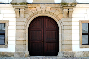 beautiful old arched brown wooden gate to residential home. vintage european street. stucco exterior elevation. stone road pavement. historic vintage building. travel and tourism concept