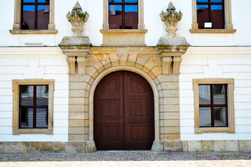 beautiful old arched brown wooden gate to residential home. vintage european street. stucco exterior elevation. stone road pavement. historic vintage building. travel and tourism concept