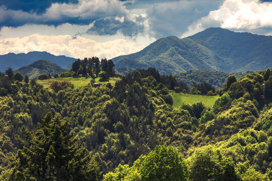 A barn on a green mountain hill in sunny spring day