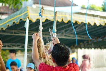A man skinning a sacrificial goat that was hung on a pole during Eid al-Adha