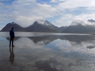 The Vestrahorn Mountains in Iceland stand tall and dramatic against the sky, their jagged peaks reflected perfectly in the calm waters below. 