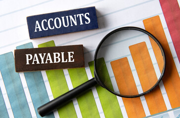 ACCOUNTS PAYABLE - words on wooden blocks on the background of a graph and a magnifying glass