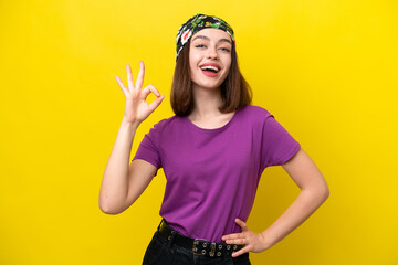 Young Ukrainian woman isolated on yellow background showing ok sign with fingers