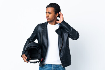 Fototapeta premium African American man with braids holding a motorcycle helmet isolated on white background having doubts