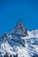 Majestic snow-capped mountain peak stands tall against clear blue sky, showcasing rugged beauty of winter landscape. Karachay-Cherkessia. Dombay 2025. Nature concept for design.