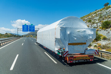 Rear view of a truck carrying an oversized load driving on a highway.Convoi exceptionnel.