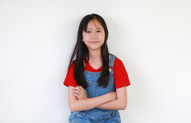 Portrait of happy Asian preteen girl standing with arms crossed and looking camera on white studio background.