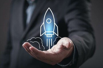 A business professional holds a hand up with a graphic of a rocket, symbolizing innovation, technology, and ambition.
