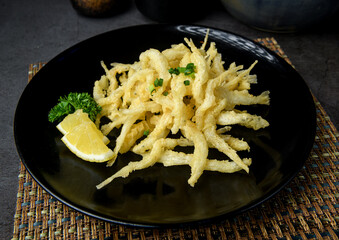 Crispy Fried Small Fish with Lemon on Black Plate