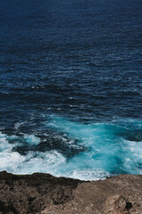 Aerial View of Rough Sea Waves Colliding with Jagged Coastal Rocks