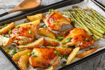 Sheet pan chicken with asparagus and potatoes close-up on a table. horizontal