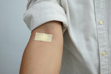Person's Arm with a Medical Adhesive Bandage After Blood Test or Vaccination