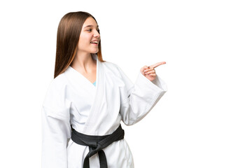 Teenager girl doing karate over isolated chroma key background pointing finger to the side and presenting a product