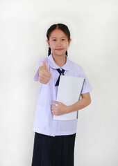 Portrait of Asian student girl in school uniform showing thumb up finger very good gesture while holding a book against white background.