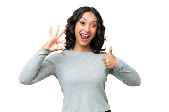 Young Argentinian woman over isolated background showing ok sign and thumb up gesture - Powered by Adobe