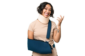 Obraz premium Young argentinian woman wearing neck brace and sling over isolated background saluting with hand with happy expression