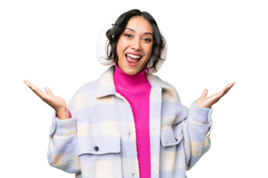 Young Argentinian woman wearing winter muffs over isolated background with shocked facial expression