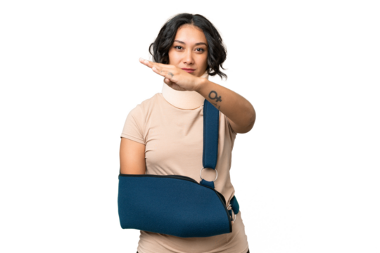 Young argentinian woman wearing neck brace and sling over isolated background making stop gesture