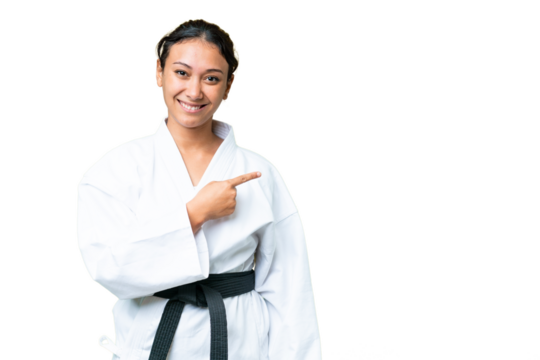 Young Uruguayan woman doing karate over isolated chroma key background pointing to the side to present a product