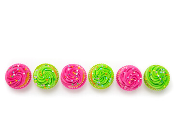 Row of colorful cupcakes with pink and green frosting arranged on white background