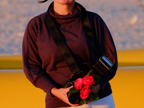 Beautiful woman under 35 years old standing on the sea and beach with a photo camera in Ruach in the hands of Rosa in black and blue shorts