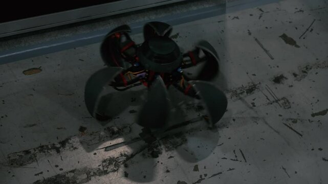 Mysterious dark robotic device spins on a gritty floor. Industrial setting. Tech concept.