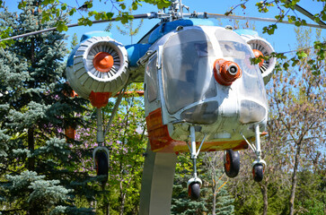 A helicopter is suspended from a tree. The helicopter is orange and white