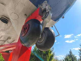 The landing gear of an airplane, with the wheels being red and black. The scene is set against a blue sky, creating a sense of calm and serenity. The contrast between the bright blue sky