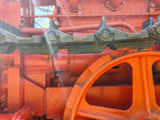 The front of a red tractor with a black wheel. The wheel is orange and has a black rim