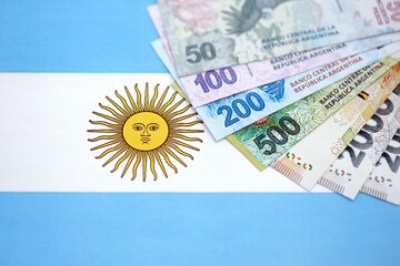 Argentine pesos money bills in big amount lies on Argentina flag close up