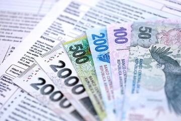 Argentine pesos money bills in big amount lies on table with pen and tax forms close up