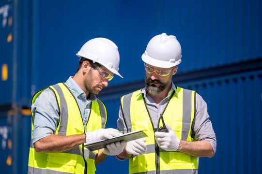 Logistics engineer and inspector working and discuss in shipping container in commercial transport port - Powered by Adobe