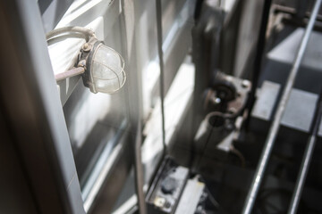 Protected light fixture with metal mesh casing in an elevator shaft, showcasing industrial safety design