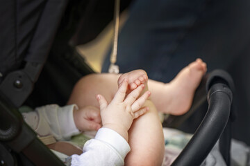 Baby in stroller demonstrates early development stage - hand-foot interaction, a precursor to crawling