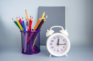 The concept back to school. Books, school stationery and an alarm clock