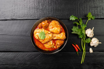 Chicken curry Asian food masala. Traditional cooking healthy food with spices. Arranged on black wooden table background.