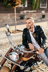 Obraz premium Biker smiling and sitting on a motorcycle in the city