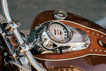 Chrome motorcycle speedometer and fuel tank detailing reflecting urban landscape