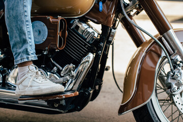 Motorcyclist placing foot on footrest of brown motorcycle