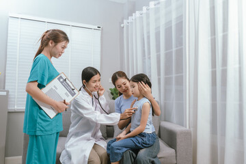 Obraz premium A smiling doctor examines a cute little girl at home, providing gentle care and health advice in a warm atmosphere.