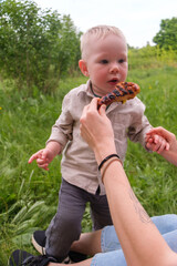 Laughing toddler outdoors with grilled chicken drumstick at picnic