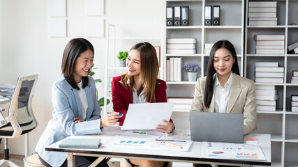 Three women are sitting at a table in a business setting, smiling
