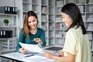 Obraz premium Two women are sitting at a desk with papers in front of them